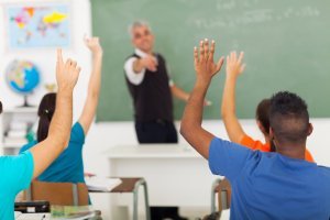 students raising hands in classroom